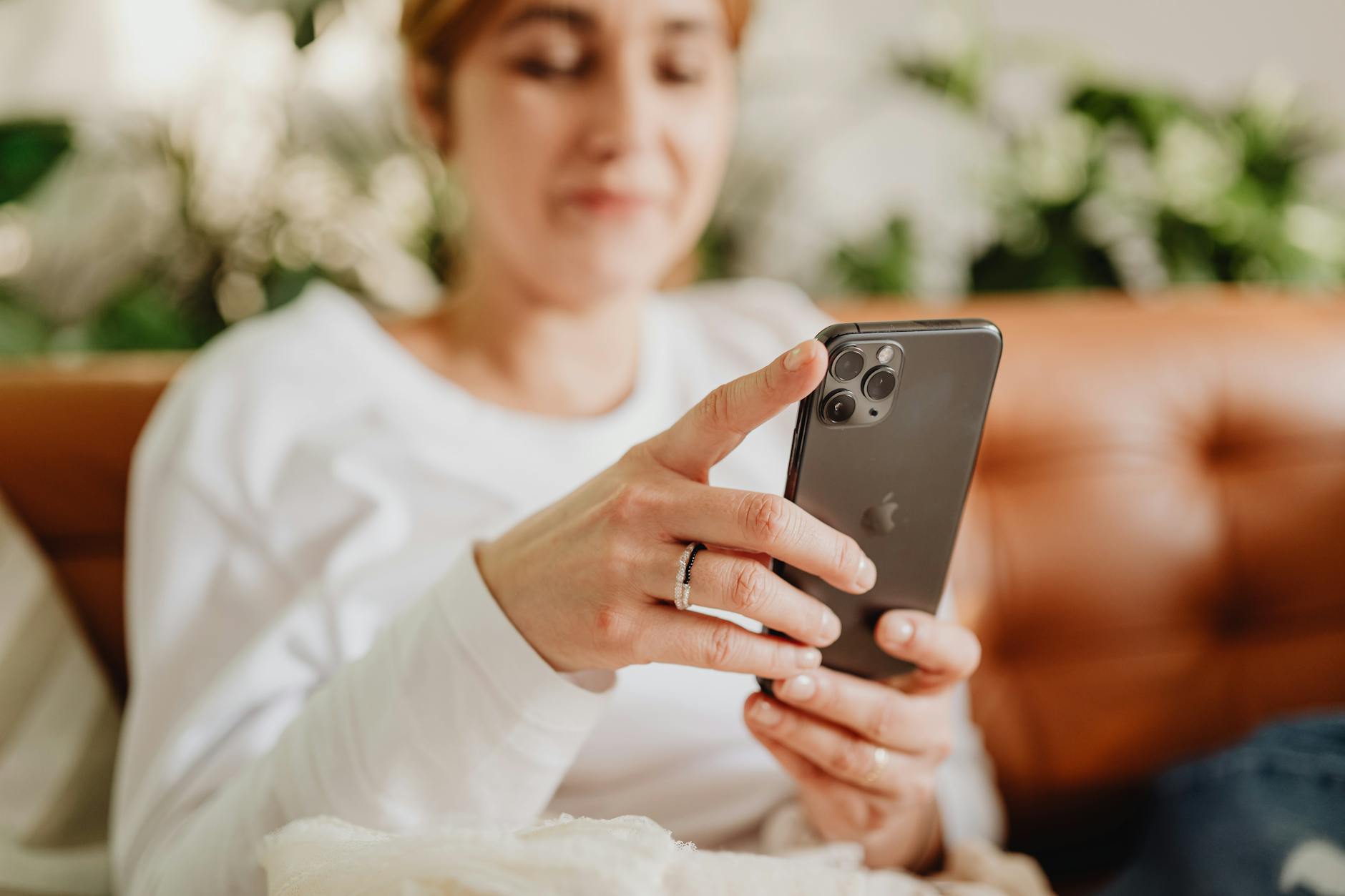 Kobieta na kanapie przegląda smartfon, odpoczywając w domu
