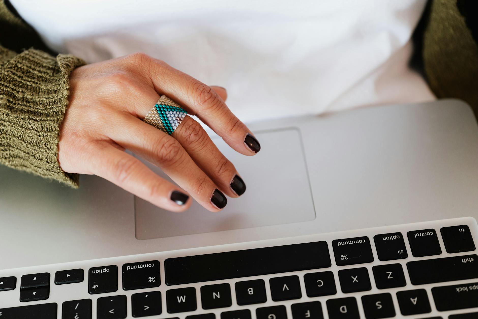 Kobieta z pierścieniem smart ring przy laptopie, z dłońmi na touchpadzie