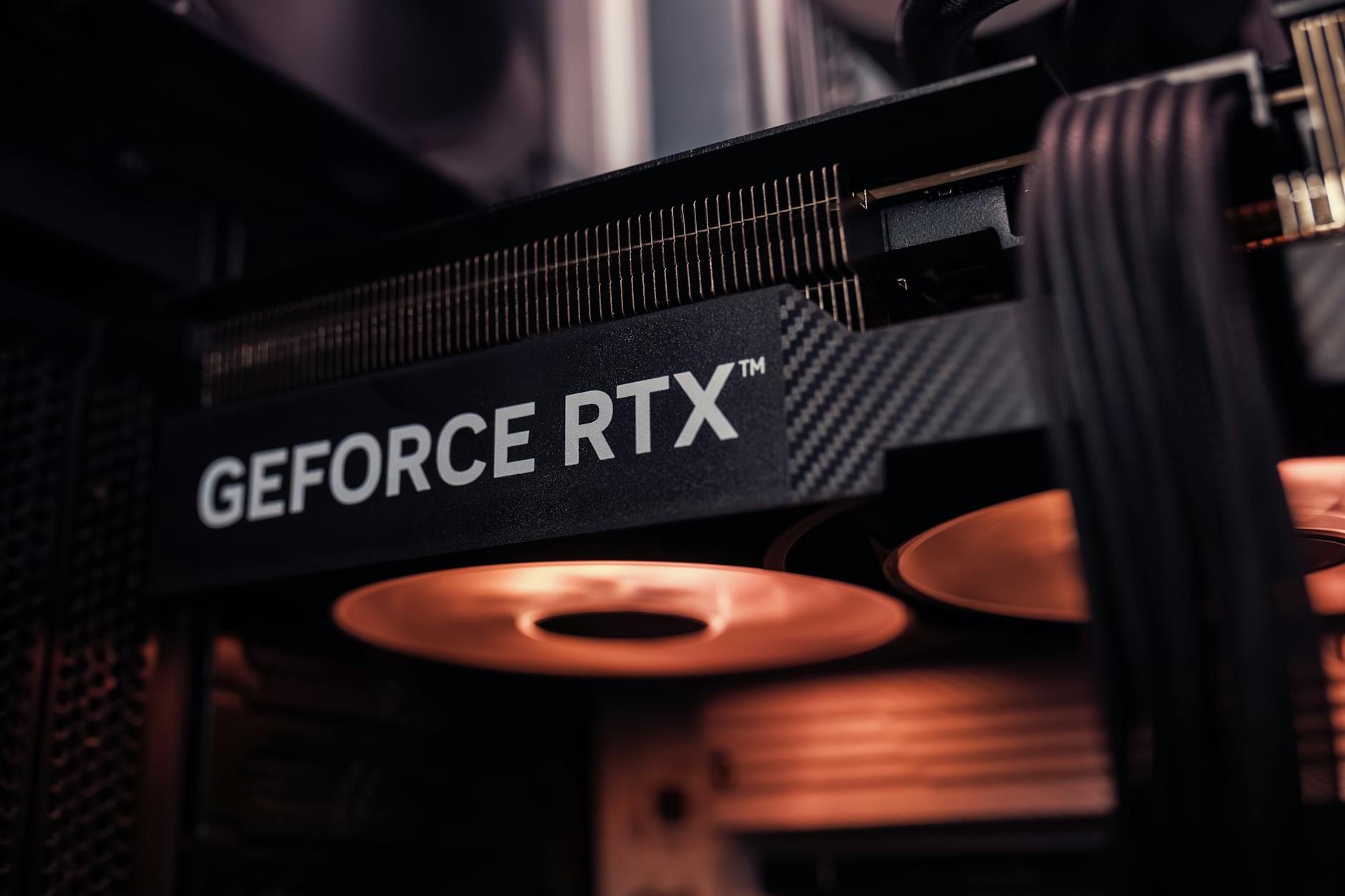 Karta graficzna GeForce RTX w obudowie komputera, podświetlona na ciepło