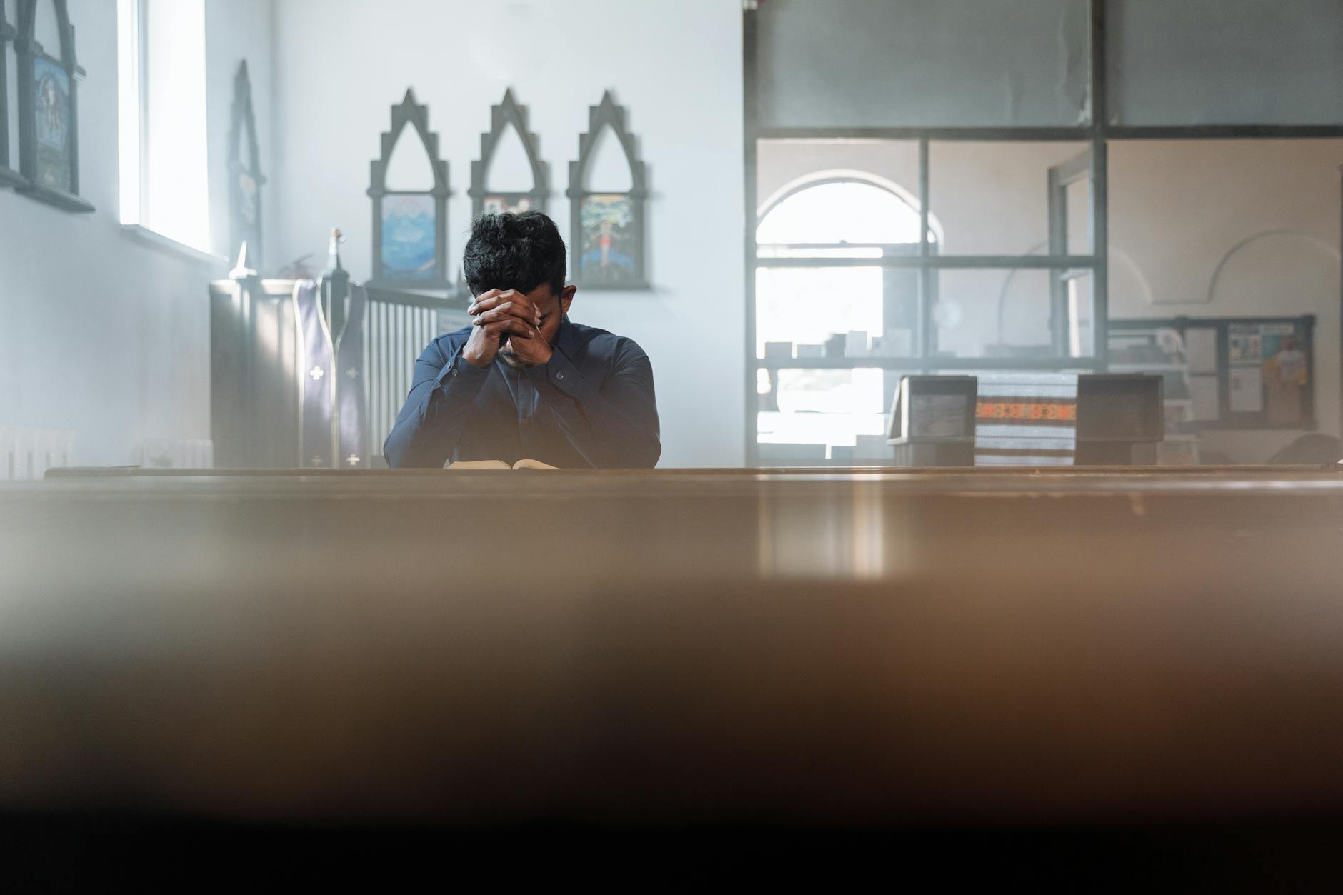 Mężczyzna modli się w nasłonecznionym pokoju, szukając odnowy wiary