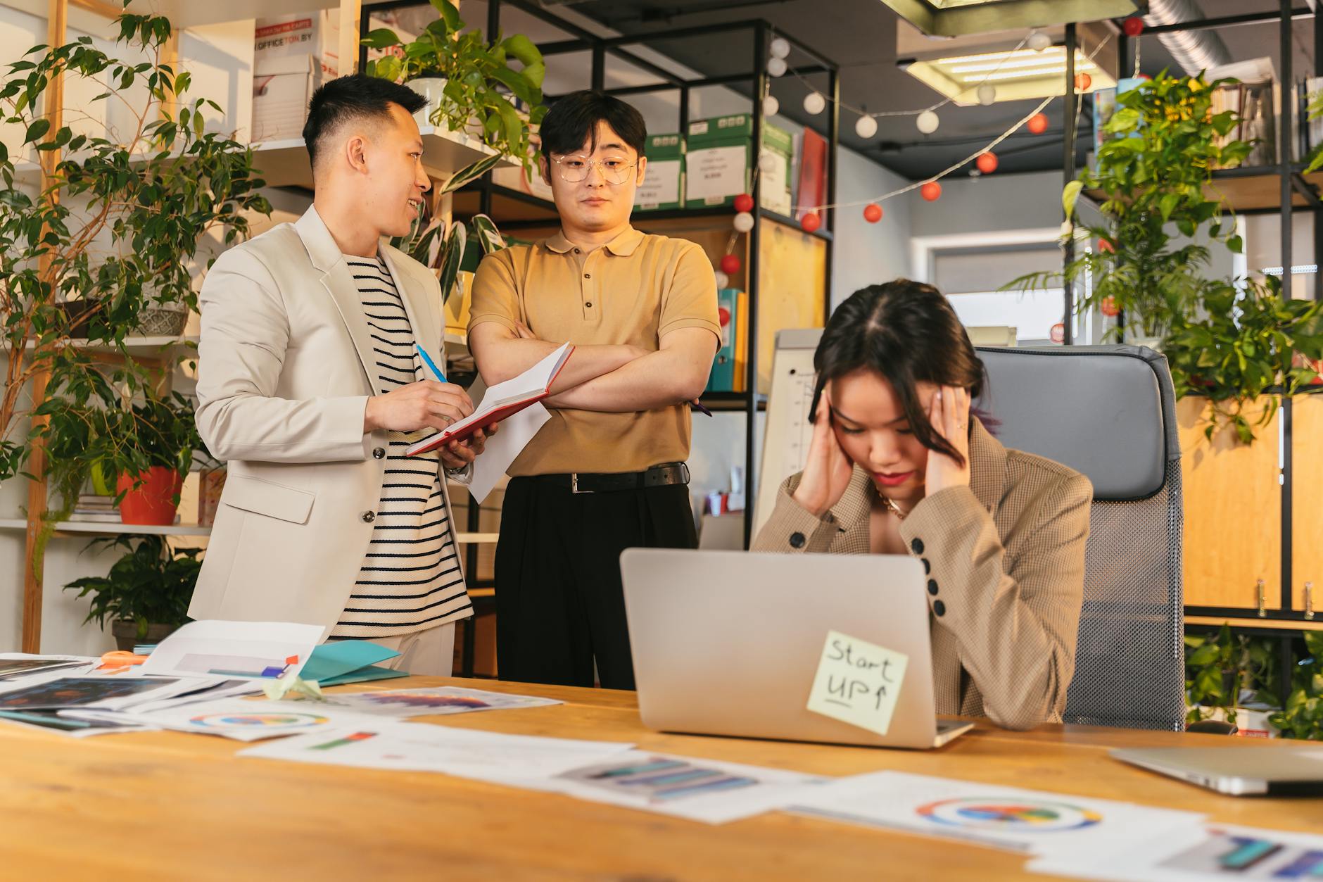Specjaliści IT rozmawiają przy dokumentach w nowoczesnym biurze z roślinami