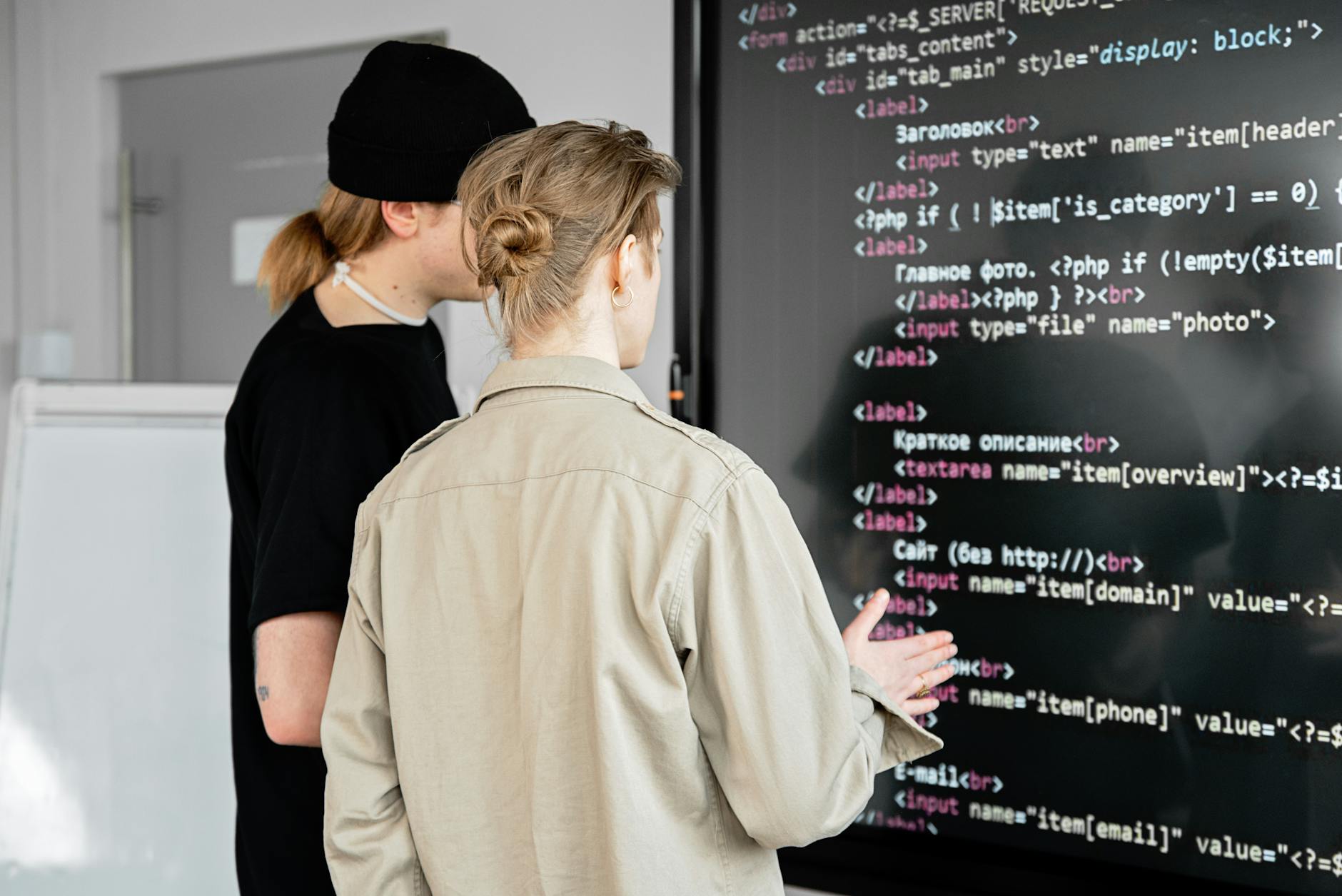 Dwóch programistów analizuje kod open source na dużym ekranie w biurze