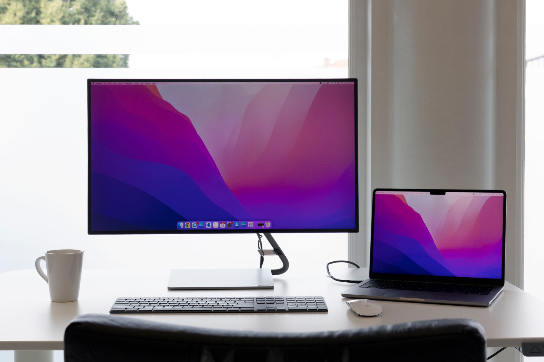Minimalistyczne biurko z dwoma monitorami, laptopem i klawiaturą