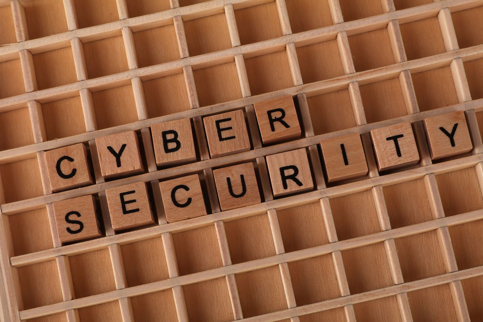Drewniane klocki układające się w napis cyber security na drewnianej planszy